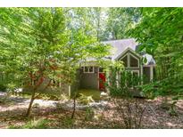 Charming gray home exterior featuring a striking red front door and lush, mature landscaping surrounding the property at 5314 Taproot Ln, Durham, NC 27705