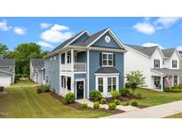 Charming blue two-story home featuring a balcony, landscaped front yard, and classic architectural details at 8925 Lee Brown Ridge Dr, Wake Forest, NC 27587