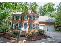 Charming two-story brick home with manicured landscaping, shutters, and a two-car garage at 104 Tutbury Pl, Cary, NC 27519