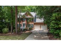 Traditional brick home featuring a two-car garage, gabled roof, blue shutters, and a well-maintained front yard at 104 Tutbury Pl, Cary, NC 27519