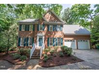 Charming two-story brick home with blue shutters, a two-car garage, and lush landscaping at 104 Tutbury Pl, Cary, NC 27519