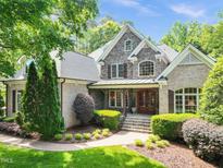A beautiful brick and stone home with a manicured lawn, lush greenery, and an inviting entryway at 10540 Byrum Woods Dr, Raleigh, NC 27613