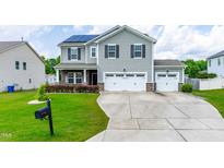 Two-story home with gray siding, black shutters, solar panels, well-manicured lawn, and a two car garage at 1104 Arden Trace Ct, Fuquay Varina, NC 27526