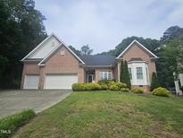 Charming single Gathering home featuring a brick facade, well manicured lawn and attached two car garage at 11221 Paddy Hollow Ln, Raleigh, NC 27614