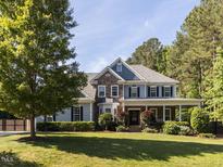 Charming two-story home with a stone and blue facade, a well-manicured lawn, and a welcoming front porch at 1201 Kalworth Rd, Wake Forest, NC 27587