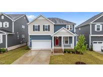 Charming two-story home featuring a red front door, a well-manicured lawn, and an attached garage at 125 Shadowdale Ln, Rolesville, NC 27571