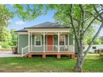 Charming home with a welcoming front porch, red door, and beautifully landscaped front yard at 129 E Chestnut Ave, Wake Forest, NC 27587