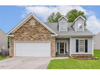 Charming home with stone accents, dormer windows, attached two-car garage, and well-maintained lawn at 149 Hutson Ln, Clayton, NC 27527