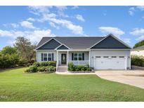 Charming single-story home with a well-manicured lawn, flower beds, and attached two-car garage at 174 Tafton Dr, Wendell, NC 27591