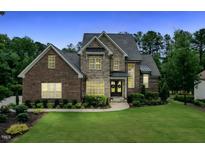 Elegant brick and stone home with manicured lawn and lush landscaping, featuring a welcoming double-door entrance at 2028 Pleasant Forest Way, Wake Forest, NC 27587
