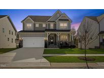 Charming two-story home with a welcoming front porch and well-manicured lawn at twilight at 204 Woodstaff Ave, Wake Forest, NC 27587