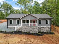 Charming one-story home featuring gray siding, a stone foundation, and a welcoming front porch with a bright red door at 249 Fisherman Point Rd, Roxboro, NC 27574