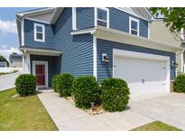 Two-story home featuring blue siding, a two-car garage, and manicured landscaping with lush green bushes at 3913 Massey Pointe Ct, Raleigh, NC 27616