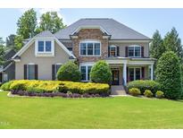 Stately two-story home with stone accents, manicured lawn, and mature landscaping at 4953 Mashpee Ln, Apex, NC 27539