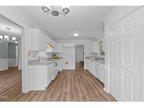 Bright kitchen features white cabinetry, granite countertops, and wood-look flooring at 5401 Lower Creek Ct, Apex, NC 27539