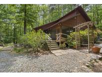 Charming cabin with inviting screened porch and wooden architectural garden feature at 5604 Hideaway Dr, Chapel Hill, NC 27516