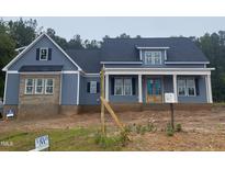 Charming blue home featuring brick accents, black shutters, and a welcoming front porch at 60 Stream View Way, Spring Hope, NC 27882