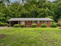 Charming single-story brick home with a well-manicured lawn and mature trees, providing a serene and inviting curb appeal at 605 Mace Rd, Mebane, NC 27302
