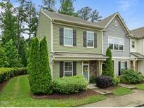 Charming two-story townhome featuring a light-green facade, black shutters, and well-maintained landscaping at 7871 Allscott Way, Raleigh, NC 27612