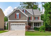 Charming two-story home featuring a stone facade, two-car garage, and a welcoming front porch, surrounded by lush greenery at 851 Dotson Way, Apex, NC 27523