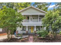 Charming two-story home with a vibrant yellow front door and welcoming double-decker front porches at 1011 Burch Ave, Durham, NC 27701