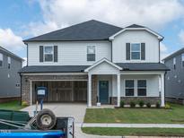 Two-story home showcasing modern design, attached two car garage, and an inviting covered front porch at 1104 Landen Creek Ln, Zebulon, NC 27597