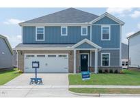 Charming two-story home featuring blue siding, brick accents, a two-car garage, and a well-maintained front lawn at 1108 Landen Creek Ln, Zebulon, NC 27597