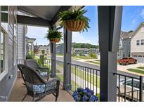 Inviting covered porch with wicker furniture, hanging ferns, and neighborhood views at 117 Banning Dr, Pittsboro, NC 27312