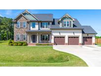 Beautiful two-story home with manicured lawn, three car garage, and stone and siding details at 173 Vinson Park Dr, Archer Lodge, NC 27527
