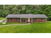 Charming brick home featuring a cozy front porch and well-maintained lawn at 1837 Garrett House Trl, Burlington, NC 27215