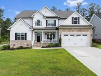 Charming two-story home featuring a landscaped lawn, brick accents, and a two-car garage at 211 Education Dr, Spring Lake, NC 28390