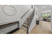 Bright entryway features stylish staircase, hardwood floors, and a decorative round mirror for a welcoming ambiance at 2634 Turner Pines Dr, New Hill, NC 27562