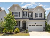 Charming two-story home with a manicured lawn, a two car garage and elegant gray and white color scheme at 2885 Farmhouse Dr, Apex, NC 27502