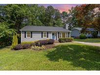 Charming one-story home featuring a well-manicured lawn and lush landscaping at 305 Burkwood Ln, Raleigh, NC 27609