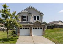 Two-story home with vinyl siding, brick base, and two-car garage beneath a blue sky on a sunny day at 3507 Portico Ln, Durham, NC 27703