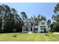 Charming two-story white farmhouse with black shutters, manicured lawn, and a welcoming front porch at 4104 Bankshire Ln, Raleigh, NC 27603