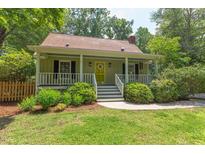 Charming front exterior view of a quaint home, featuring a well-manicured lawn and covered front porch with yellow door at 520 Brittany Bay W, Raleigh, NC 27614