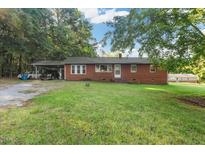 Charming single-story brick home with a spacious front yard, mature trees, and a convenient carport at 586 New Hope Church Rd, Apex, NC 27523
