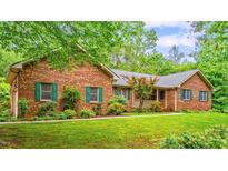 Charming brick home with lush green lawn and mature trees providing shade and curb appeal at 5939 Florasaline Dr, Mebane, NC 27302