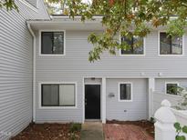 Charming townhome features gray siding, black front door, and brick entryway for a welcoming curb appeal at 7353 Sandy Creek Dr, Raleigh, NC 27614