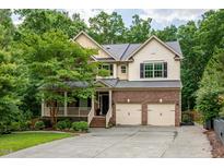 Charming two-story home features a brick facade, two-car garage, and a cozy front porch surrounded by lush landscaping at 776 Legend Oaks Dr, Chapel Hill, NC 27517