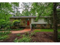Charming brick home with a well-manicured lawn, mature trees, and a welcoming red front door at 803 Churchill Dr, Chapel Hill, NC 27517