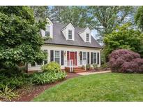 Charming home with a manicured lawn, red door, and dormer windows at 912 Salem Woods Dr, Raleigh, NC 27615