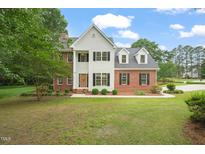 Charming two-story home featuring a manicured lawn, brick accents, and a classic design with dormer windows at 1005 Barmkin Pl, Knightdale, NC 27545