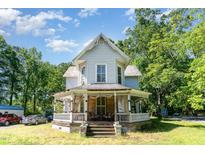Charming two-story home featuring a classic front porch and mature trees on a sunny day at 110 E Church St, Creedmoor, NC 27522