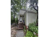 View of the home's front door with wooden steps and an inviting, landscaped entrance surrounded by lush greenery at 130 Beechwood Dr, Carrboro, NC 27510