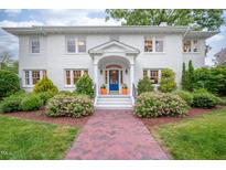 Charming two-story brick home featuring a blue front door and lush, landscaped front yard at 1519 Hermitage Ct, Durham, NC 27707