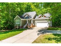 Charming home with green siding, brick accents, manicured lawn and an extended driveway at 166 Daffodil Ln, Clayton, NC 27527