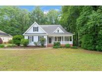 Charming light-blue home with a welcoming front porch and beautifully landscaped front yard at 1870 Lennox Dr, Garner, NC 27529