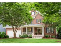 Charming brick two-story home featuring a welcoming front porch and lush landscaping at 203 Witheridge Ct, Apex, NC 27502